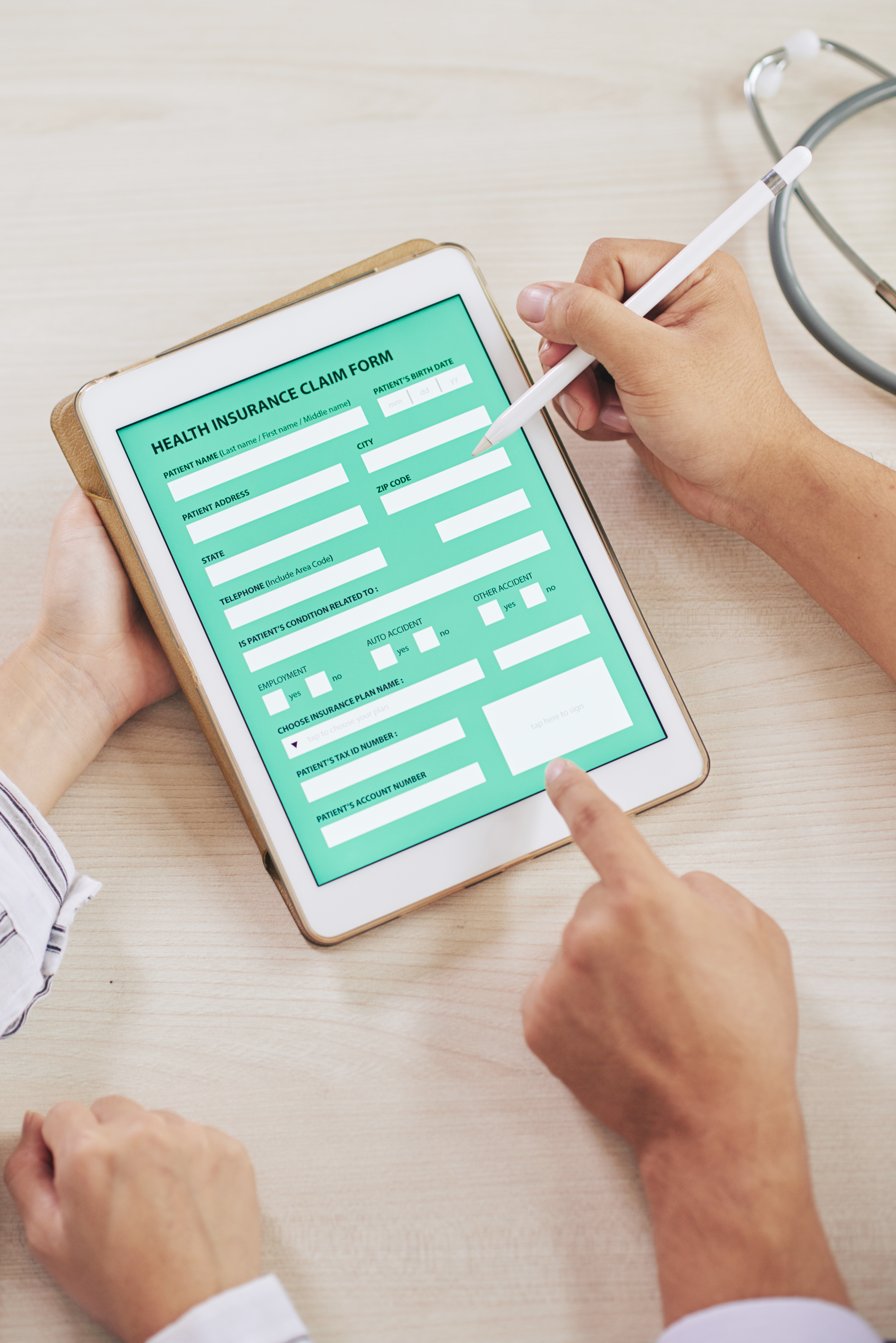 Health insurance claim form on a tablet with stylus and stethoscope